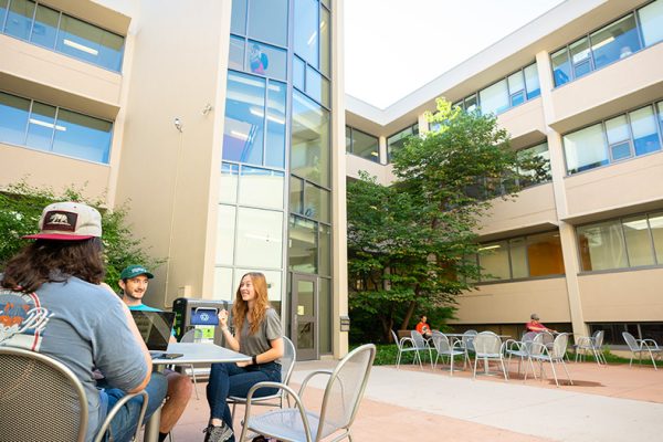outdoor shot of CSU's eddy hall. students sit outside at tables studying and eating