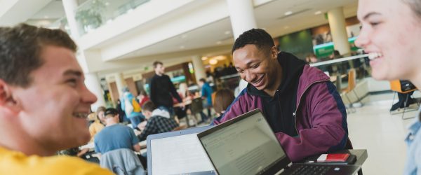 Three students with smiles at student center table